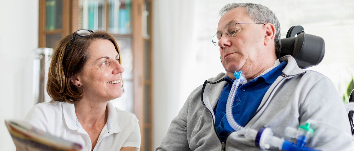 Pflegekraft liest mit Patienten in einer Zeitschrift